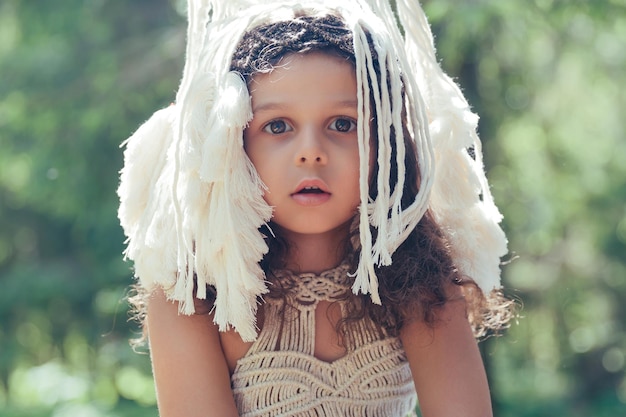 Bambina con capelli ricci scuri vestita da indigena nella foresta