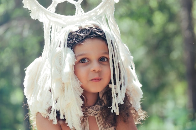 Bambina con capelli ricci scuri vestita da indigena nella foresta