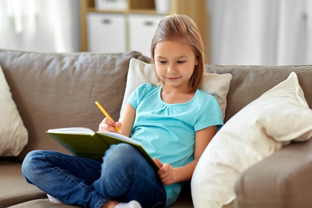 little girl with diary sitting on sofa at home