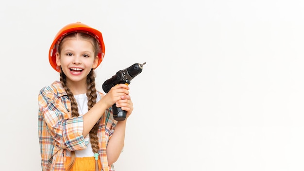 Маленькая девочка с дрелью в руках, чтобы показать вашу рекламу на белом изолированном фоне Концепция ремонта в детской комнате Копирование пространства