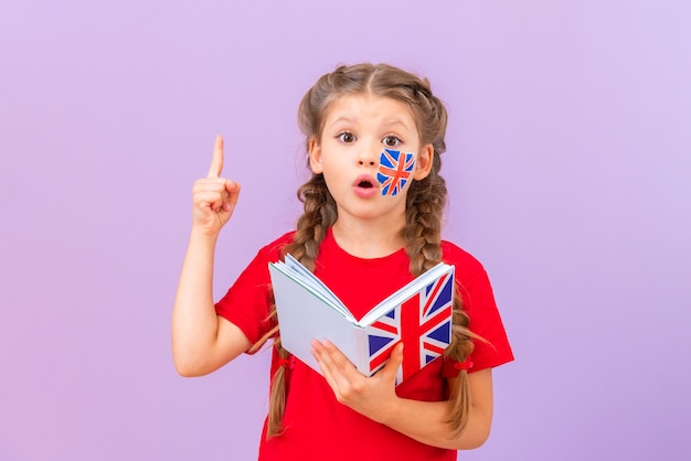 Foto una bambina con un libro in inglese indica sorpresa.