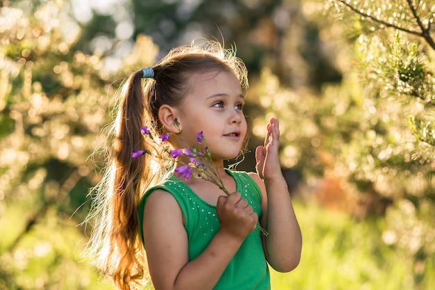 little girl with flowers bells on nature in summer