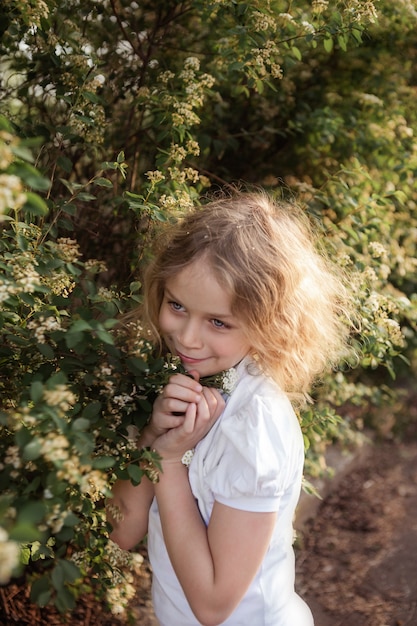 Little girl with flowers, portrait near blooming bush, close up. Spring time. Spring time concept.
