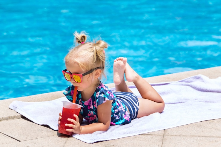Photo little girl with fresh cocktail on swimming pool in the summer day