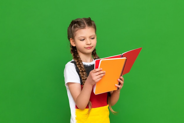 A little girl with a german flag on her tshirt is studying a
foreign language textbook on a green isolated background education
in germany and obtaining a certificate