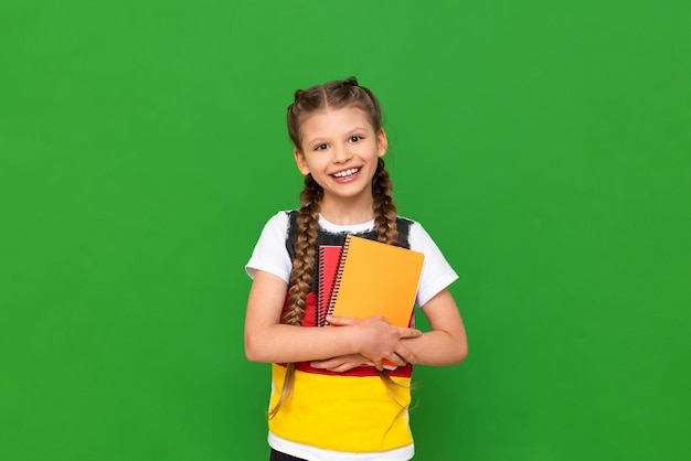 A little girl with a german flag on her tshirt is studying a
foreign language textbook on a green isolated background education
in germany and obtaining a certificate