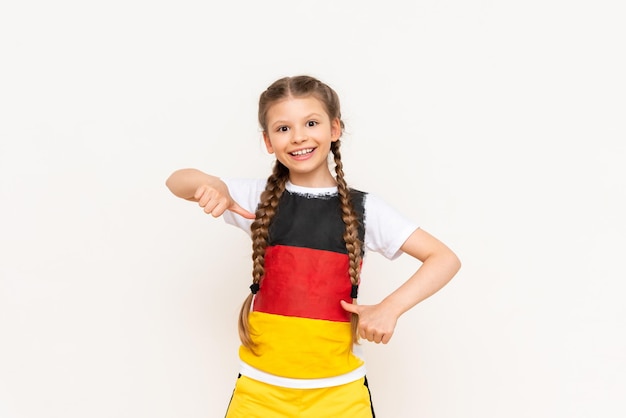 A little girl with a German flag on a Tshirt with long hair braided in pigtails on a white isolated background Language courses for children Space for copying