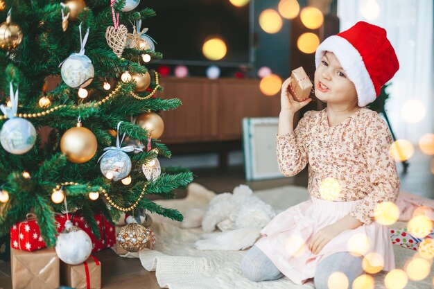 Little girl with gift box near the Christmas tree