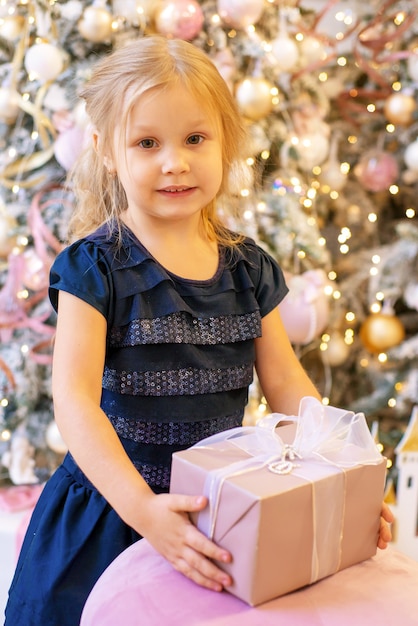 little girl with a gift near the christmas tree at christmas