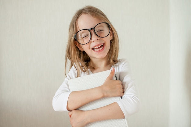 Little girl with glasses does homework reads books