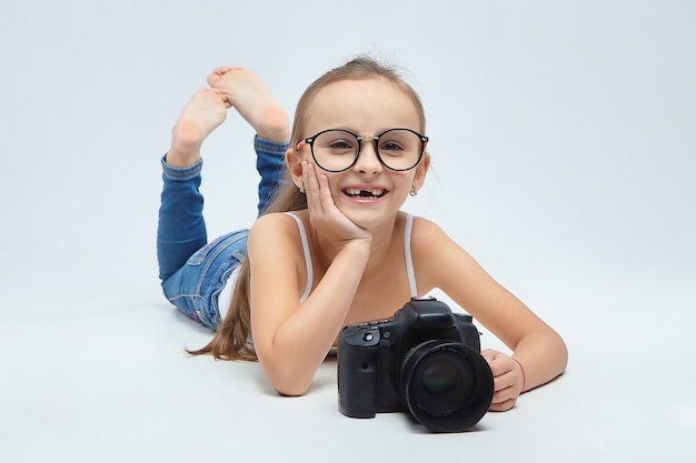 Little girl with glasses, lying in the Studio with a camera.