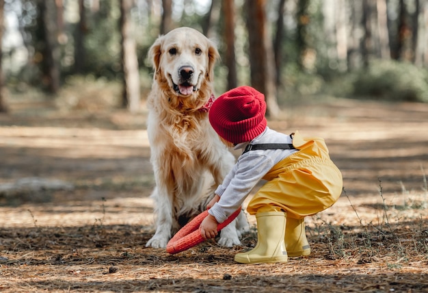 Little girl with golden retriever dog in the forest