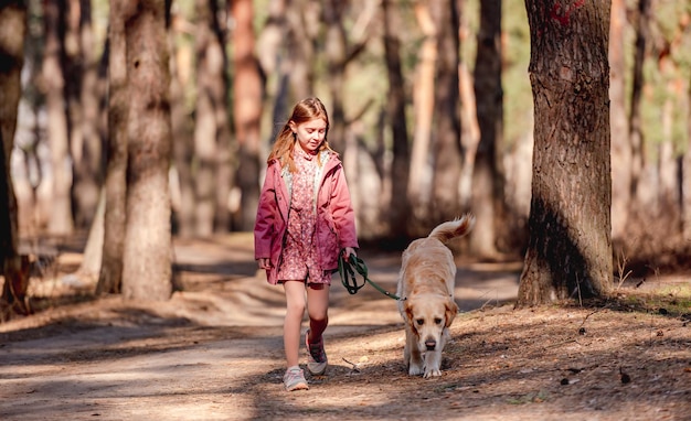 Little girl with golden retriever dog in the wood