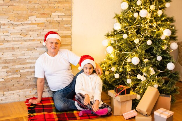 Bambina con il nonno seduto sul pavimento a durante il natale, bambina e nonni in soggiorno durante il natale.