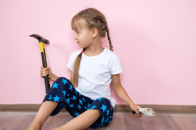 little girl with a hammer makes repairs in the children's room