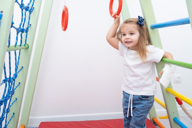 Little girl with hand in cast using sports complex at home.