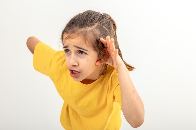 Little girl with hand near ear listening rumor hearing gossip on isolated