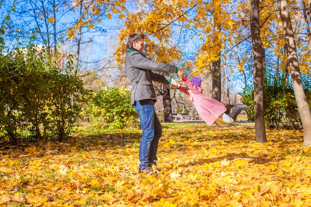 晴れた日に秋の公園で楽しんで幸せな父と小さな女の子