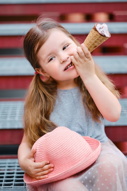 Little girl with hat eating ice cream