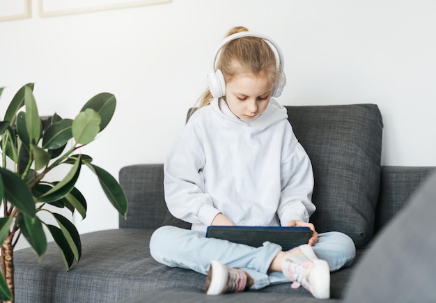 Little girl with headphones and tablet at home