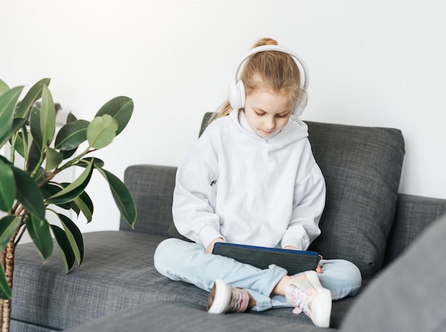 Little girl with headphones and tablet at home