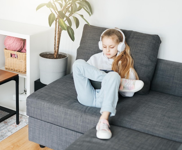 Little girl with headphones and tablet at home