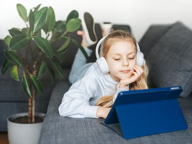 Little girl with headphones and tablet at home