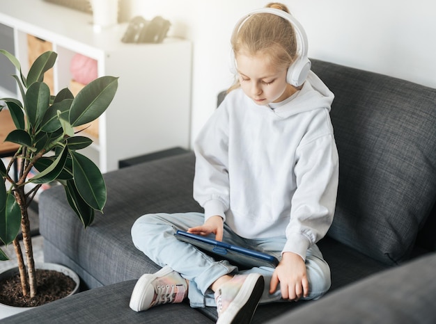 Little girl with headphones and tablet at home