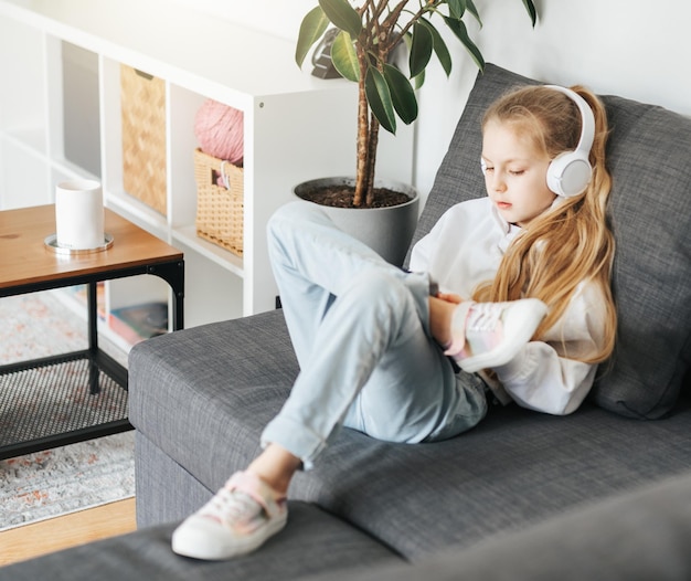 Little girl with headphones and tablet at home