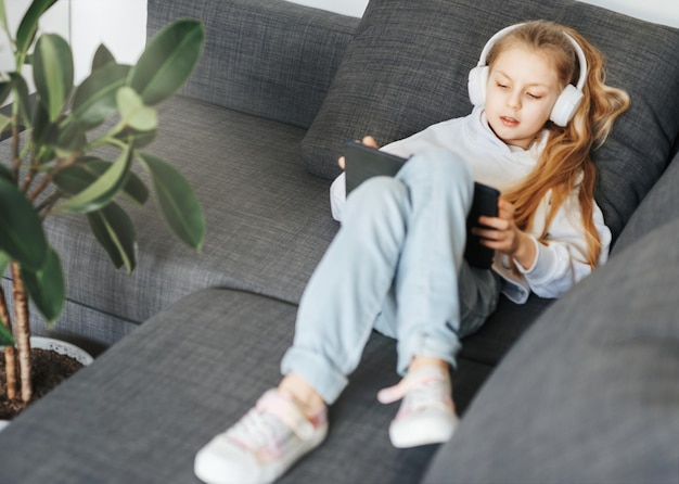 Little girl with headphones and tablet at home