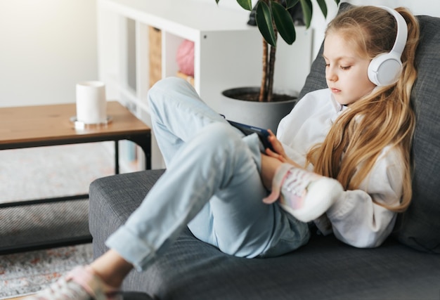 Little girl with headphones and tablet at home