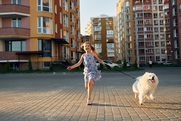 彼女の犬と一緒に小さな女の子が通りを散歩しています