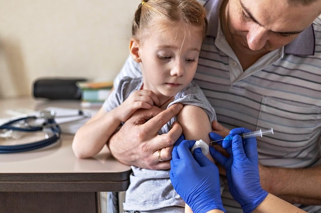 Photo a little girl with her father in the doctors office  the concept of vaccination against covid-19