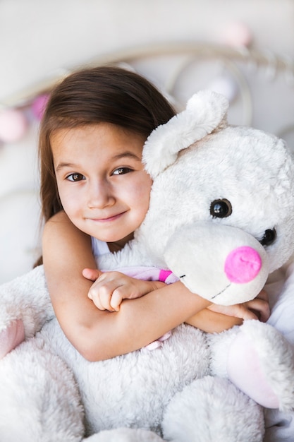 Little girl with her teddy sitting on the bed. home, comfort, family, relationships, people