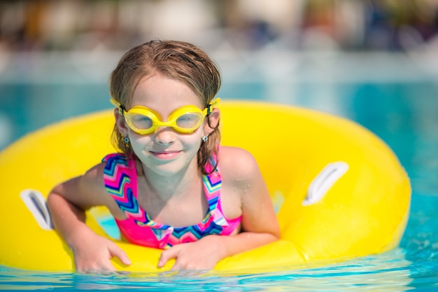 Little girl with inflatable rubber circle in swimming pool