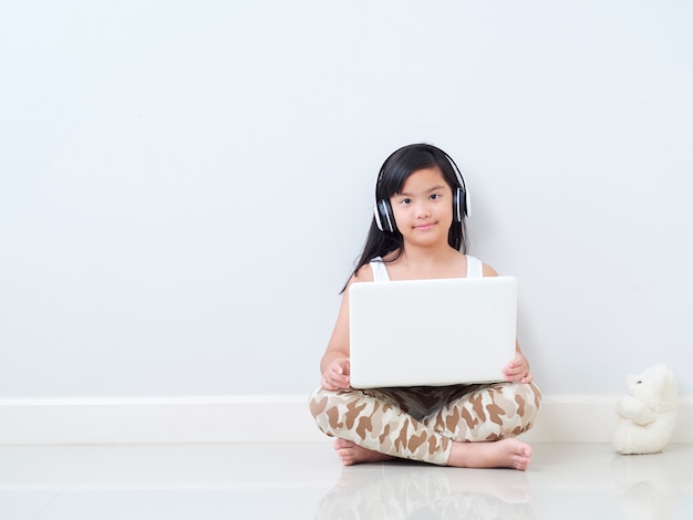 Little girl with laptop sitting on floor.