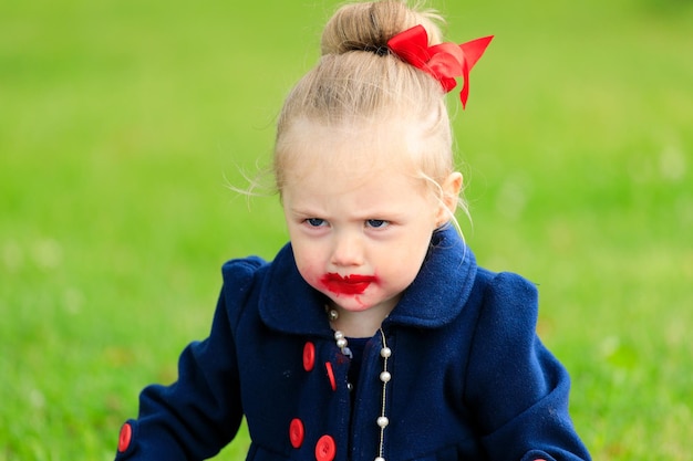 маленькая девочка с испачканным помадой лицом