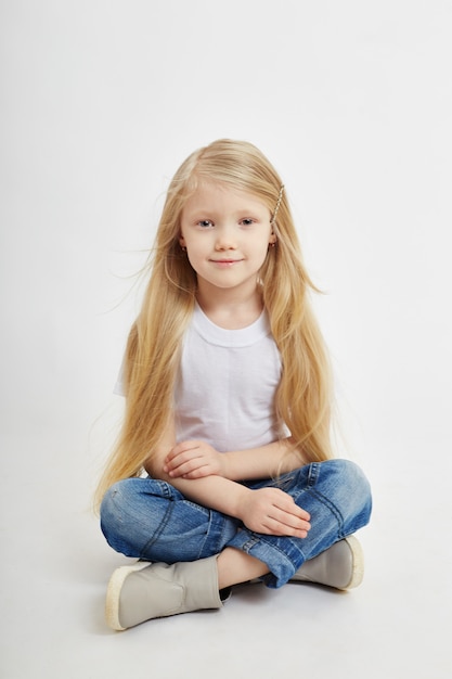 Маленькая девочка с длинными светлыми волосами и в джинсах