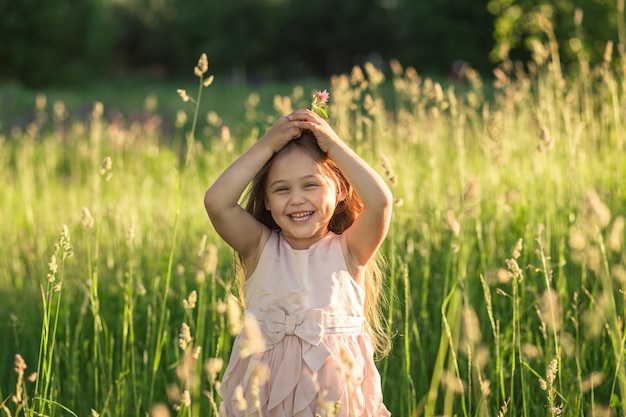 little girl with long hair in a beautiful dress on the nature in summer