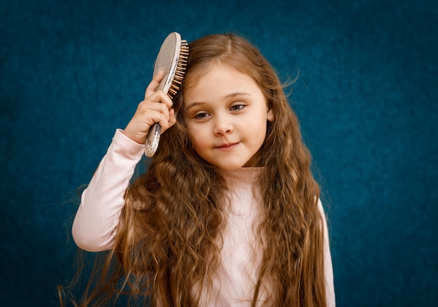 Photo little girl with long hair is combed by a comb