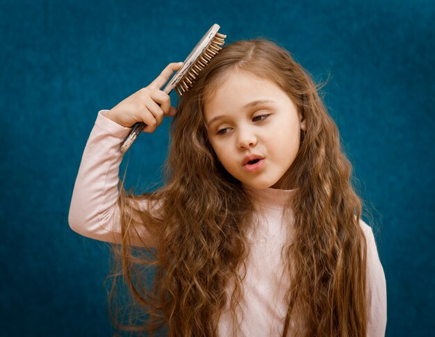 Little girl with long hair is combed by a comb