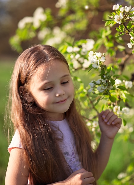 Little girl with long hair near a flowering tree