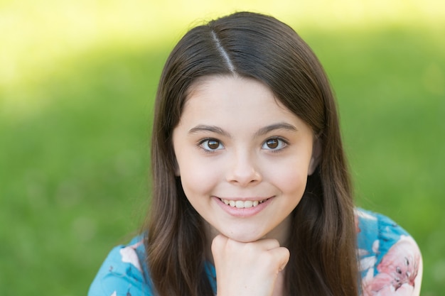 Little girl with long hair relaxing in park sunny day green grass background adorable smile concept