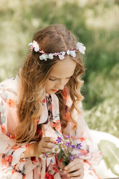 Little girl with long white hair and a bouquet of wildflowers in the park