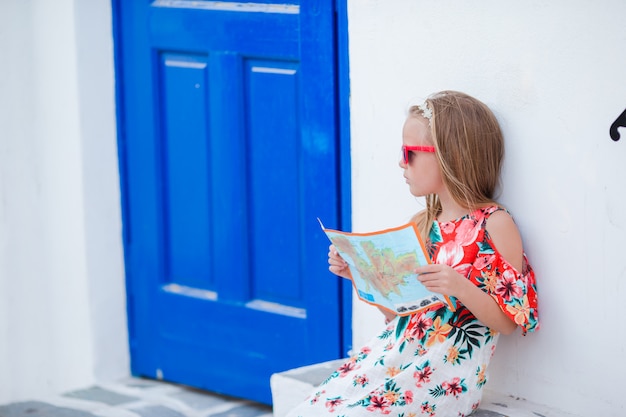 Bambina con la mappa dell'isola all'aperto in vecchie strade un mykonos.