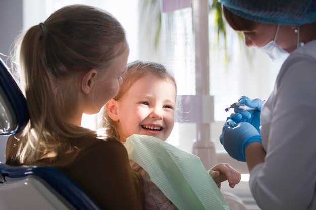 Little girl with mommy in dentist chair - child is smiling, close up