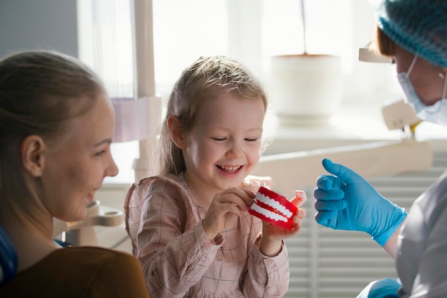 Little girl with mommy in dentist room - conversation with doctor, close up