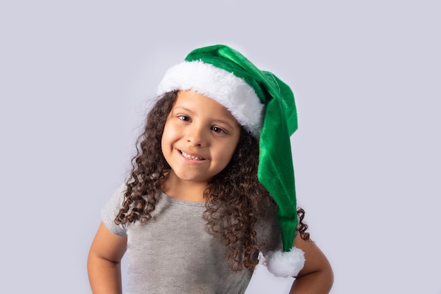 Little girl with Mrs. Claus green hat on gray