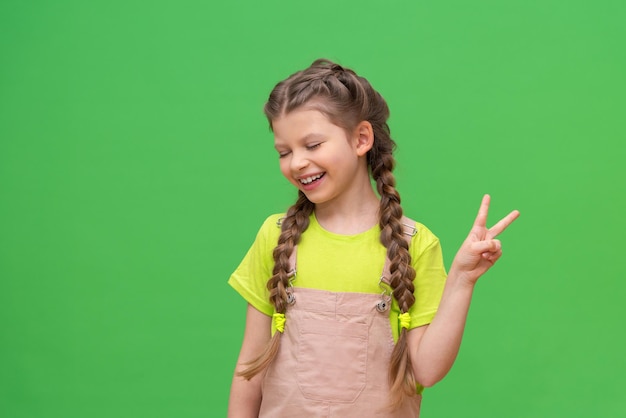 A little girl with pigtails shows two fingers. Children on an isolated background.