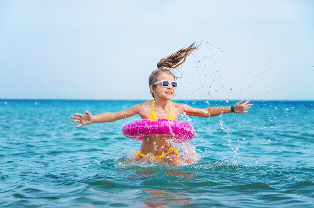 Little girl with pink round inflatable in the sea